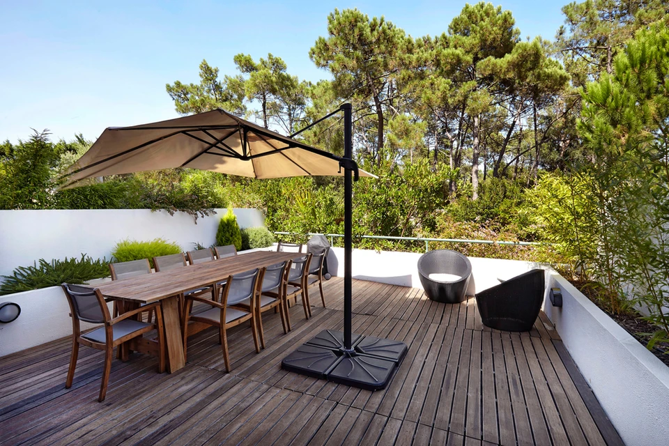 Terrasse extérieure moderne avec table à manger en bois et chaises assorties sous parasol déporté beige