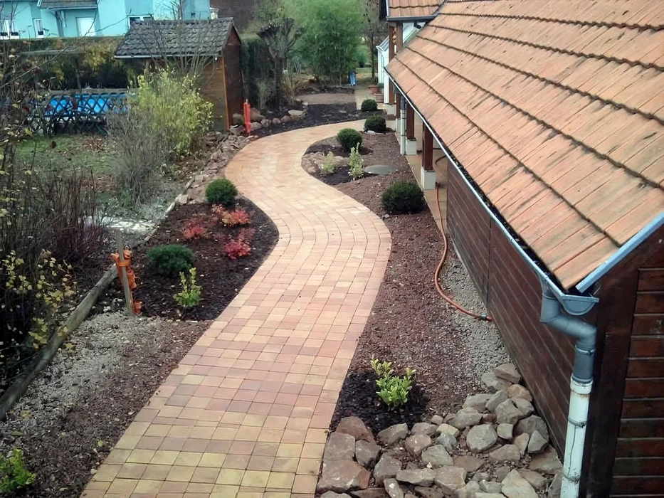 Aménagement paysager extérieur résidentiel avec allée courbe en pavés autobloquants beiges et roses