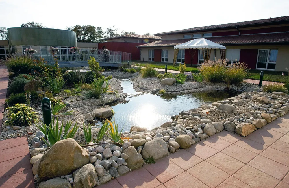 Aménagement paysager extérieur avec bassin d'ornement entouré de galets et pierres naturelles