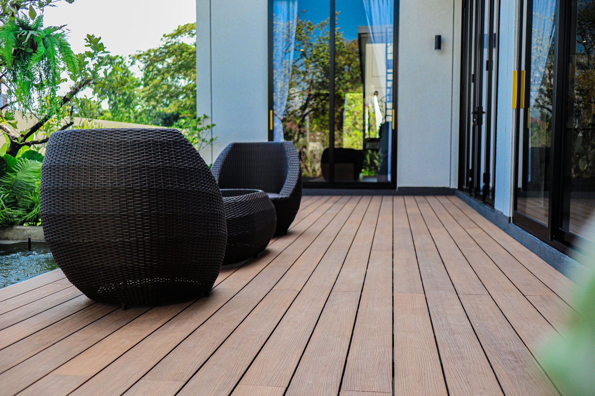 Terrasse extérieure aménagée avec mobilier en bois massif comprenant banquettes modulaires avec coussins gris anthracite, table basse assortie et brasero métallique noir